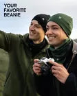 Woman and man wearing beanies with a camera in the foreground