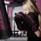 Woman training on heavy bag wearing black and pink boxing gloves