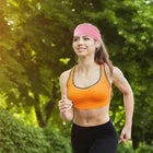 Woman in athletic wear running outdoors wearing a pink headband