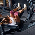 Woman using squat press wearing red knee wraps