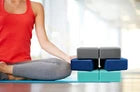 Woman using a yoga mat with a blue block on a blue surface